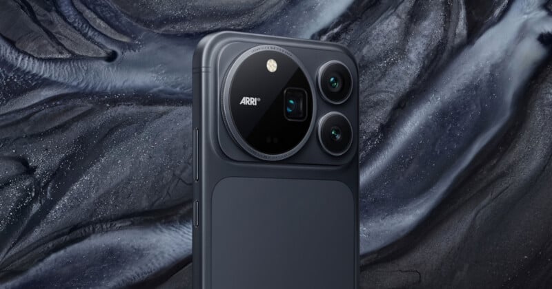 A close-up of a dark gray smartphone back featuring a large, circular camera module with three lenses and the text "ARRI" printed on it, set against a textured, abstract dark background.