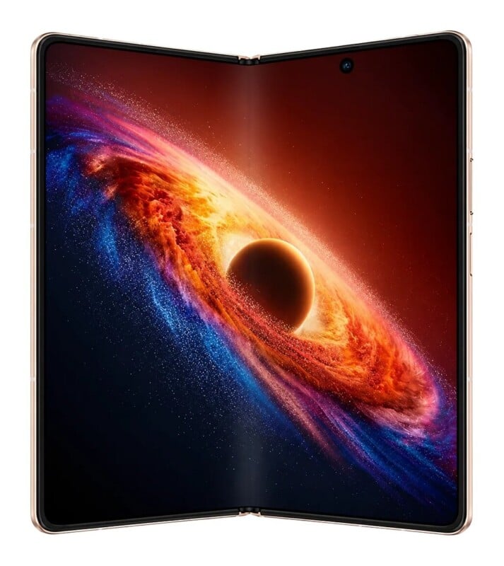 A foldable smartphone shown in its open, tablet-like state, displaying a vibrant, swirling cosmic nebula wallpaper with a dark center.