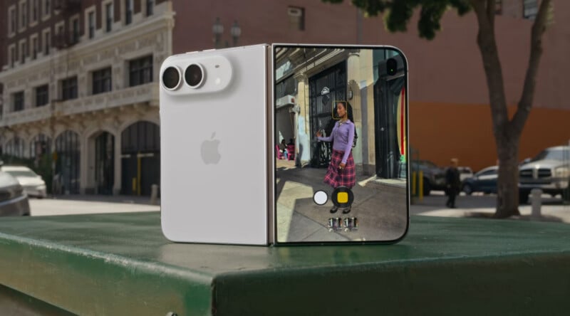 A white foldable smartphone stands upright on a green surface, displaying a camera interface on its inner screen.
