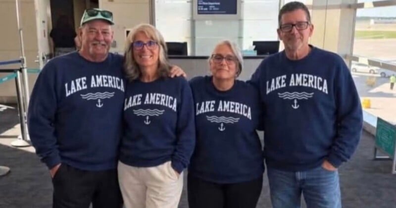 Four people stand side-by-side in an airport terminal wearing matching navy blue sweatshirts that say "LAKE AMERICA" with a wave and anchor graphic.