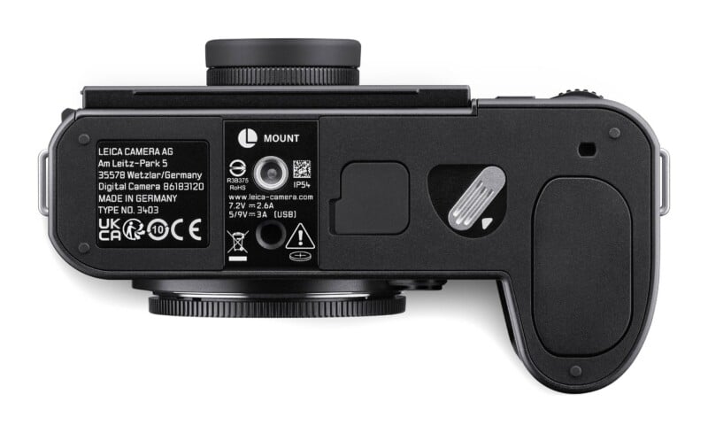 The underside of a black digital camera, showing a battery compartment latch, a tripod mount, and regulatory text including "LEICA CAMERA AG" and "MADE IN GERMANY.