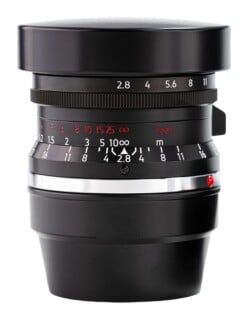 A black camera lens with a silver mounting ring, aperture markings, and distance scales in feet and meters, isolated against a white background.