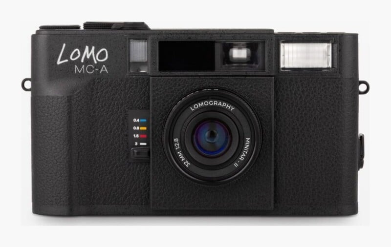 A black Lomo MC-A film camera with a 32mm 1:2.8 Minitar-II lens, featuring a zone focus slider on the front and a built-in flash.