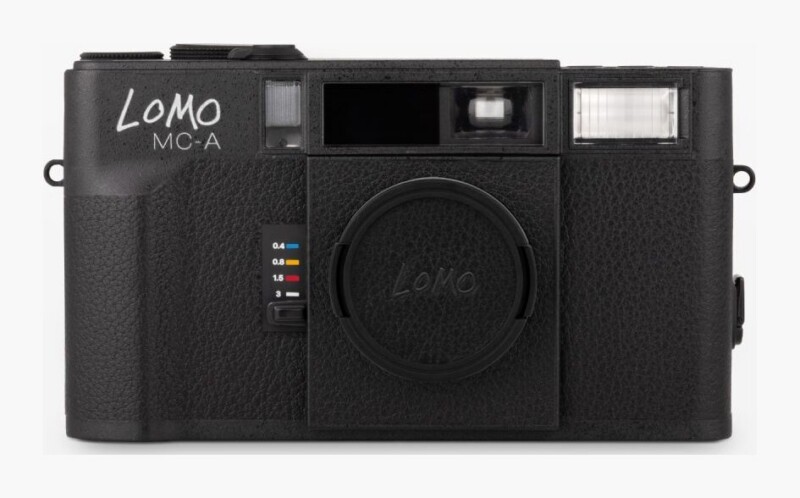 A black Lomo MC-A film camera with a lens cap, a built-in flash, and a zone-focusing switch on the front.