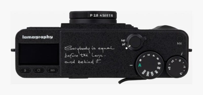 Top-down view of a black Lomography camera featuring the text "Everybody is equal before the lens - and behind it" printed on the body.