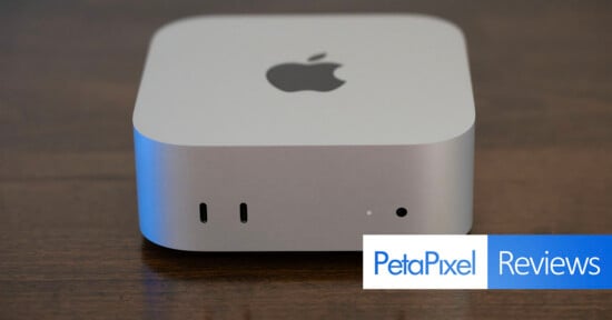 A silver Apple Mac Studio computer sits on a dark wooden surface, showing two front-facing USB-C ports, a status light, and a headphone jack, with a PetaPixel Reviews logo in the bottom right corner.