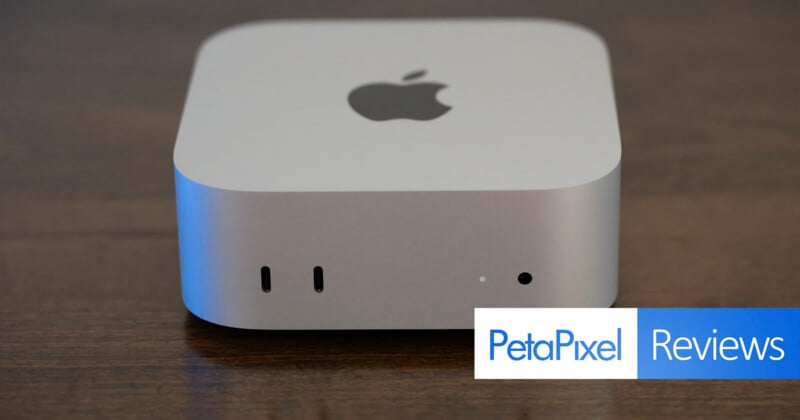 A silver Apple Mac Studio computer sits on a dark wooden surface, showing two front-facing USB-C ports, a status light, and a headphone jack, with a PetaPixel Reviews logo in the bottom right corner.