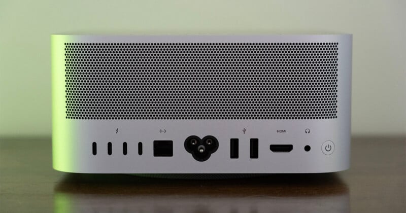The back panel of a silver computer, featuring a large ventilation grille above a row of ports including four USB-C, Ethernet, power, two USB-A, HDMI, a headphone jack, and a power button.