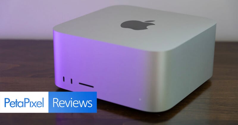 A silver Apple Mac Studio computer sits on a dark wooden surface, with a PetaPixel Reviews logo in the bottom left corner.