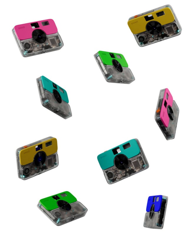 Eight digital cameras with colorful faceplates and transparent bodies are scattered against a white background.