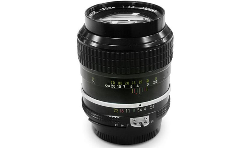 A black Nikon Nikkor 105mm f/2.5 manual focus camera lens standing upright against a white background.