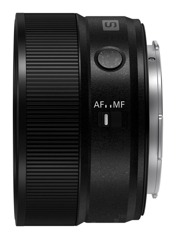 A side view of a black camera lens featuring a focus ring, a customizable function button, and an AF/MF toggle switch.