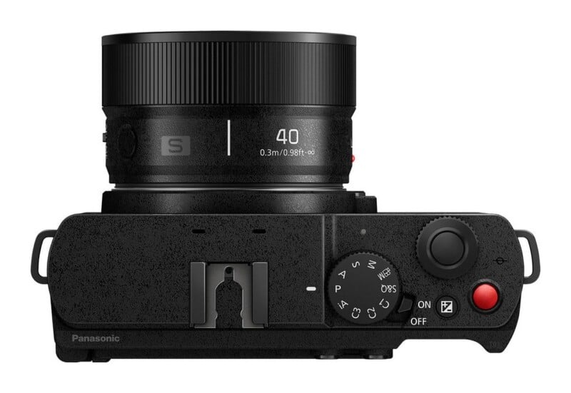 Top-down view of a black Panasonic camera with a lens attached, showing the mode dial, shutter button, and hot shoe.