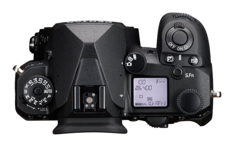 Top-down view of a black digital SLR camera body with a mode dial on the left, a hot shoe, a top LCD screen, and a shutter button on the right.