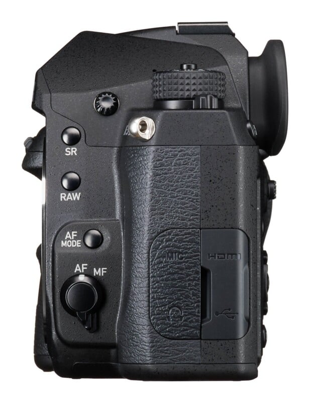 A side view of a black digital camera body showing buttons labeled SR, RAW, AF MODE, and a switch for AF/MF, along with a rubber port cover for MIC, HDMI, and USB connections.