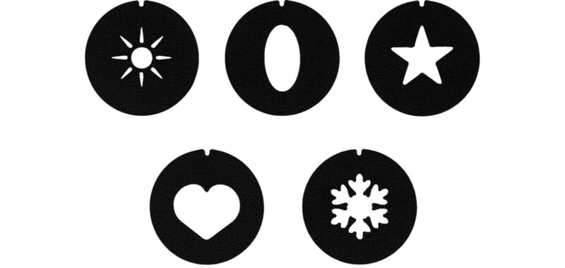 Five black circular discs, each with a small notch at the top and a unique white cutout shape in the center: a sun, an oval, a star, a heart, and a snowflake.
