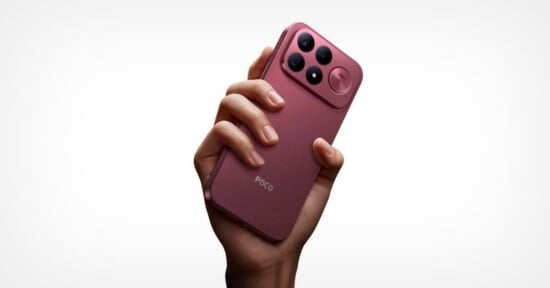 A hand holds a pink smartphone with a prominent camera module featuring three lenses and a circular accent on the back.