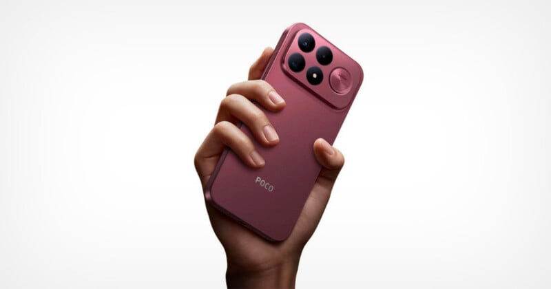 A hand holds a pink smartphone with a prominent camera module featuring three lenses and a circular accent on the back.