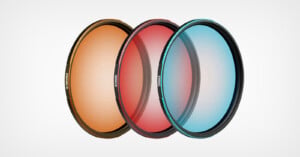 Three circular camera lens filters in orange, red, and blue are arranged in a row against a plain white background, with the text "EMANATE," "EMBER," and "EVOKE" printed on their respective frames.