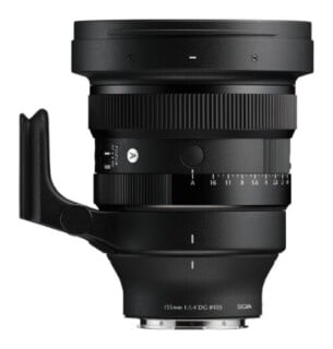 A black camera lens with a tripod mount attached to the side, featuring an aperture ring and focus switch, viewed from the side against a white background.
