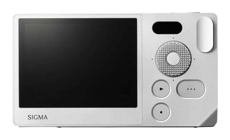 The back of a silver Sigma camera featuring a large LCD screen, a textured circular control dial, and several buttons.