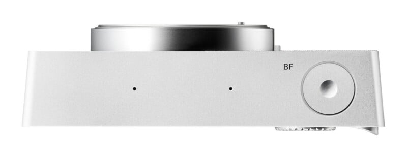 A top-down view of a silver camera body showing a circular shutter button labeled BF, two small microphone holes, and the top edge of the lens mount.