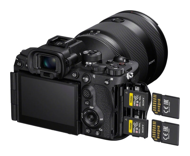 A black mirrorless camera with a lens attached, shown from the rear with its memory card slot open and two Sony CFexpress Type A memory cards inserted, with two additional identical cards positioned to the right.