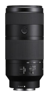 A black Sony E-mount telephoto zoom lens shown from the side, featuring focus and zoom rings, a focus hold button, and switches for OSS and focus mode.