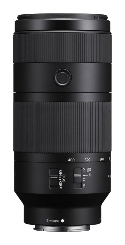 A black Sony E-mount telephoto zoom lens shown from the side, featuring focus and zoom rings, a focus hold button, and switches for OSS and focus mode.