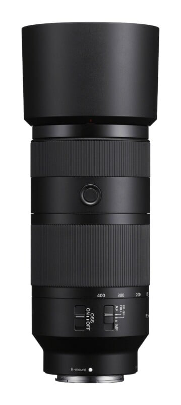 A black telephoto zoom lens for a camera, shown from the side, featuring a focus hold button, zoom ring, and switches for OSS and focus range settings.