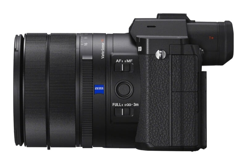 Side view of a black digital camera with a large zoom lens, featuring a Zeiss logo and focus mode switches on the barrel.