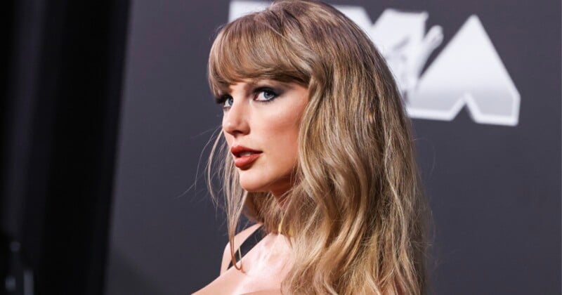 Taylor Swift with blonde hair and bangs looks over her shoulder at the camera against a dark background with partial text.