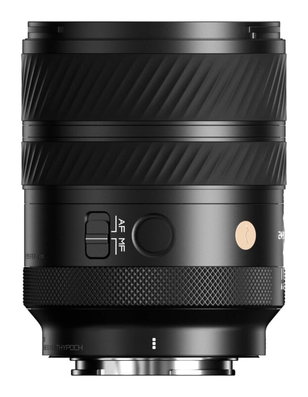 A black camera lens stands vertically against a white background, featuring a textured focus ring, an AF/MF toggle switch, a circular button, and a small gold logo.