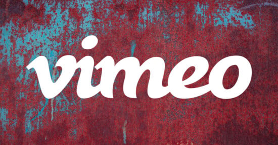 The white Vimeo logo is centered over a background of weathered, rusted metal with patches of blue paint.