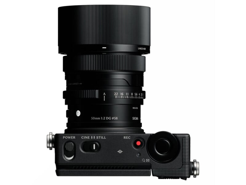 A top-down view of a black mirrorless camera with a Sigma 50mm lens attached, showing the power switch, mode selector, and shutter button.