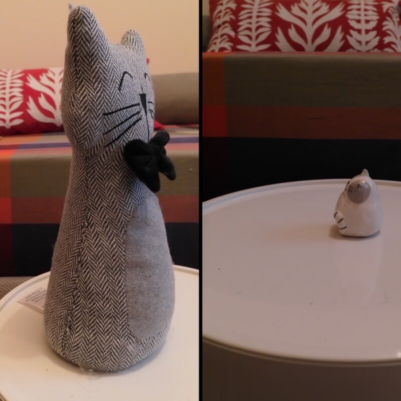 A split-screen image showing a large, fabric, herringbone-patterned cat doorstop on the left and a tiny ceramic cat figurine on the right, both sitting on a white table.