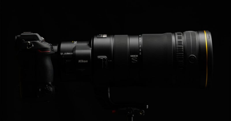 A professional camera with a large telephoto zoom lens mounted on a tripod against a black background.