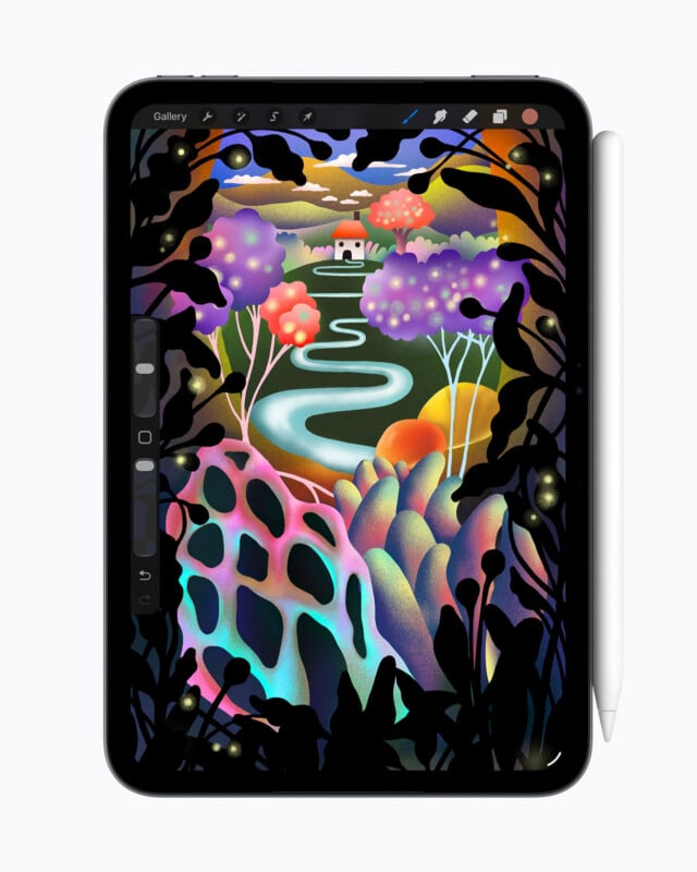A digital tablet displays a colorful, whimsical landscape illustration featuring a winding river, stylized trees, and a small house, framed by dark, silhouetted foliage.