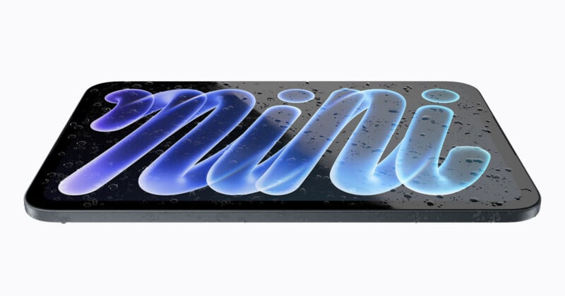 A tablet device is shown at an angle, displaying the word "mini" in stylized blue script on its screen, which is covered in water droplets.