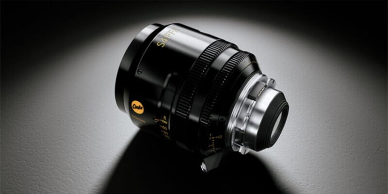 A black Cooke S4/i 50mm cinema lens sits on a dark, textured surface, illuminated by a spotlight from above.