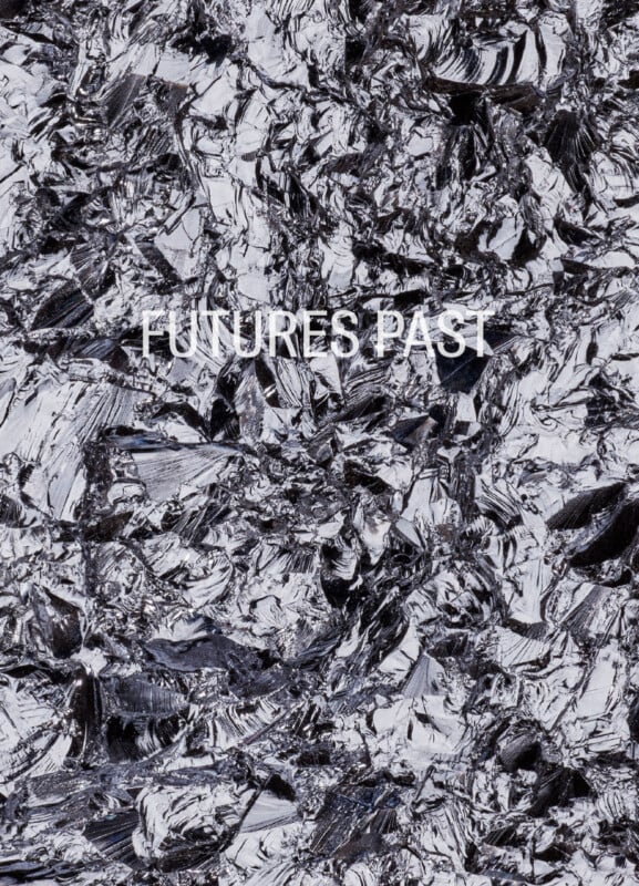 The words "FUTURES PAST" are centered in white, sans-serif text over a background of jagged, reflective black and silver shards.