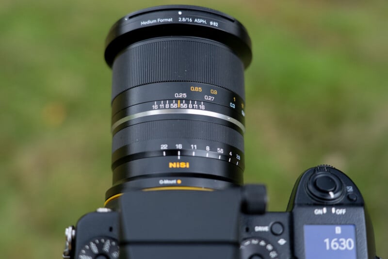 A NiSi 16mm f/2.8 medium format lens mounted on a camera, showing aperture and focus distance markings on the barrel.