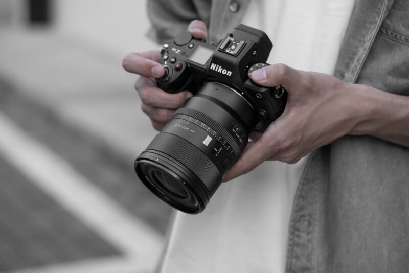 A person holds a black Nikon mirrorless camera with an AF 35/1.4 Z lens attached.