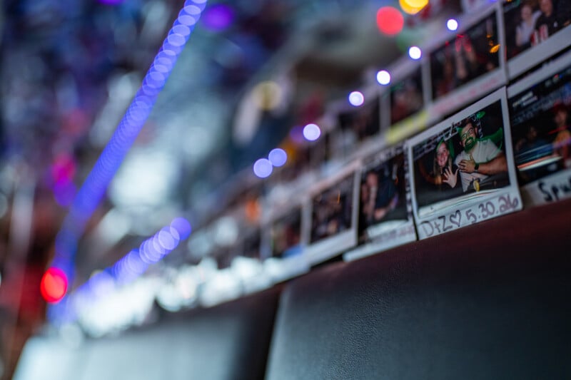 A row of polaroid photos is displayed on a dark, textured surface, with a shallow depth of field highlighting a photo labeled 