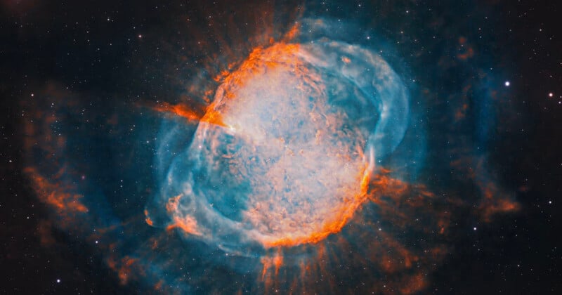 A vibrant, glowing nebula features a bright, textured central core surrounded by wispy, orange-red filaments and blue gas.