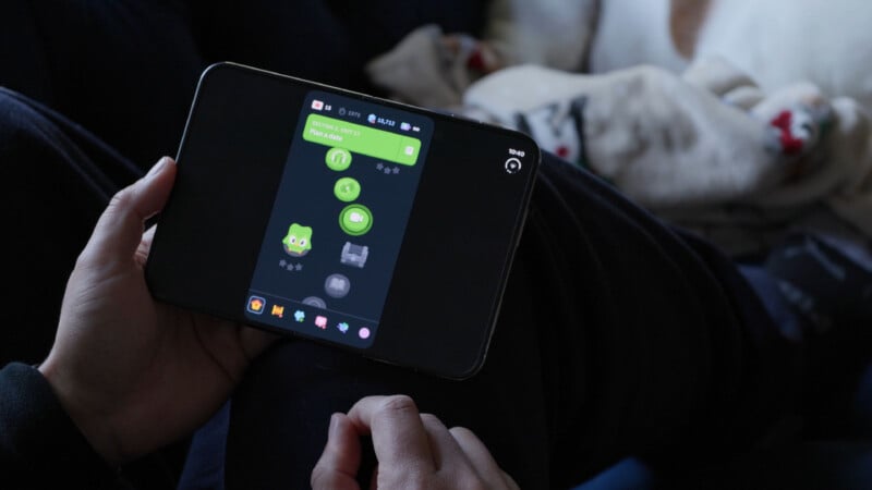 A person holds a foldable smartphone displaying the Duolingo app interface, showing a language learning path in progress.