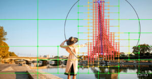 A woman in a hat and light-colored coat stands by a river, with a digital grid overlay highlighting the Eiffel Tower.