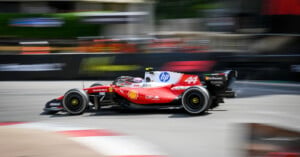 A red and white Formula 1 race car with the number 44 and HP branding drives at high speed on a track.