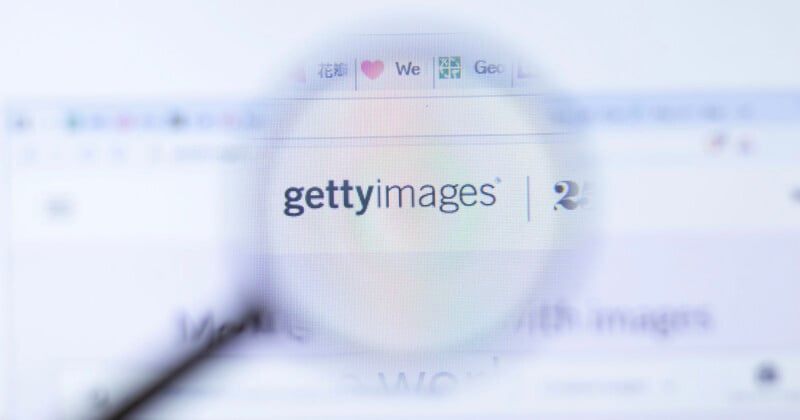 A magnifying glass is positioned over a computer screen displaying the Getty Images logo and website interface.