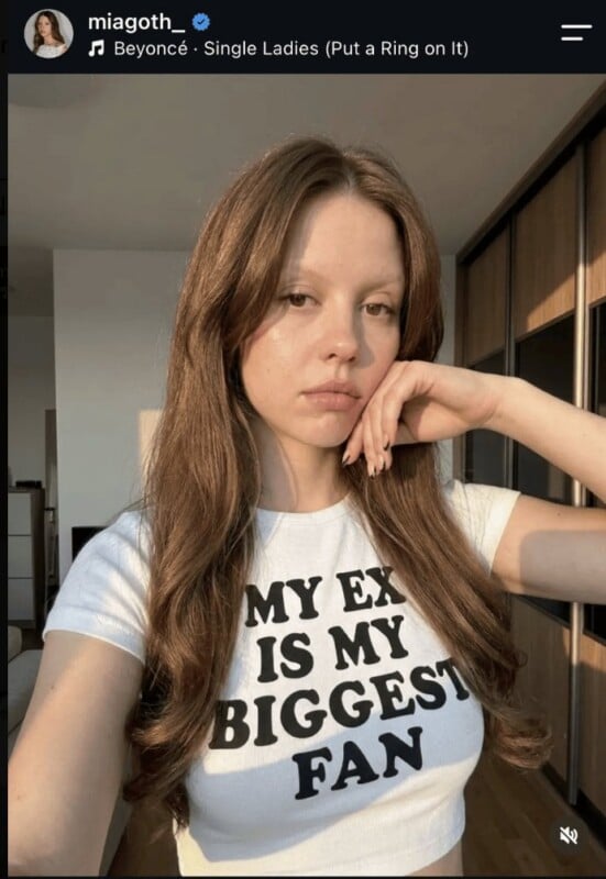 A person with long brown hair and light eyebrows wears a white t-shirt that reads "MY EX IS MY BIGGEST FAN" in black text.